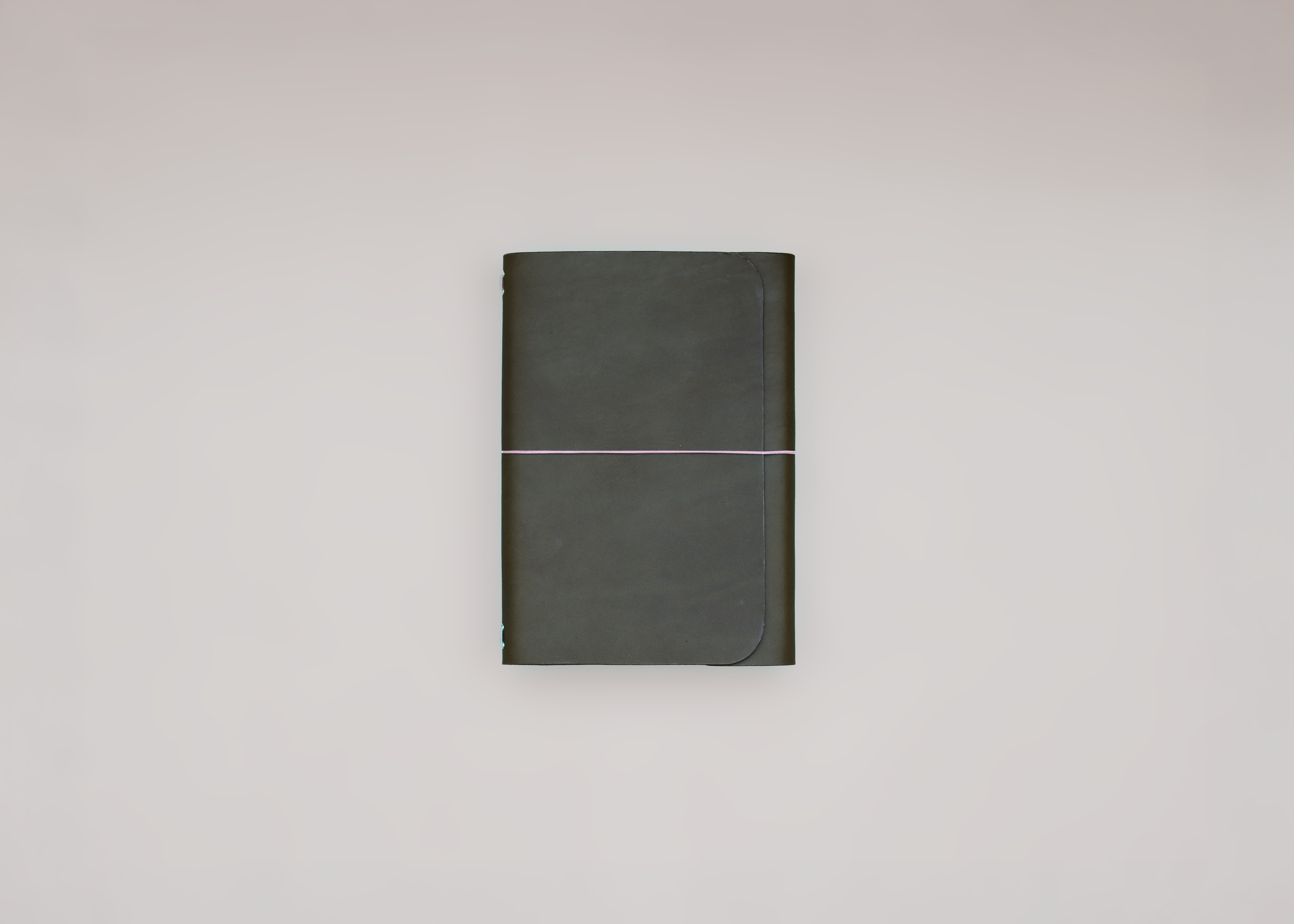 A dark olive green hardcover notebook with a thin elastic band closure, centered against a plain light gray background.