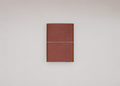 A brown leather journal with a light elastic across the front, shown closed against a neutral light gray background.